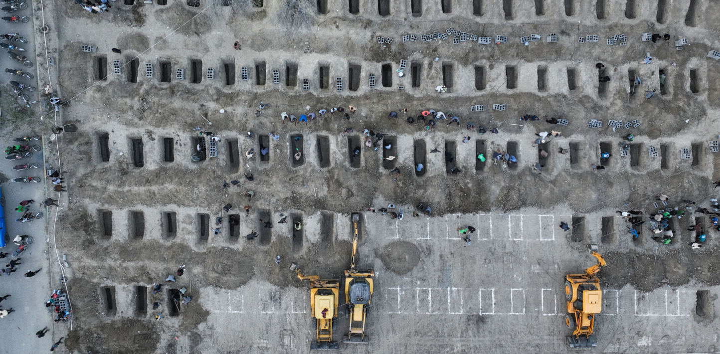 In this aerial handout picture released by the Iranian Press Center, mourners dig graves during the funeral for children killed in a reported strike on a primary school in Iran's Hormozgan province in Minab on March 3, 2026. (Photo by Iranian Press Center / AFP via Getty Images)